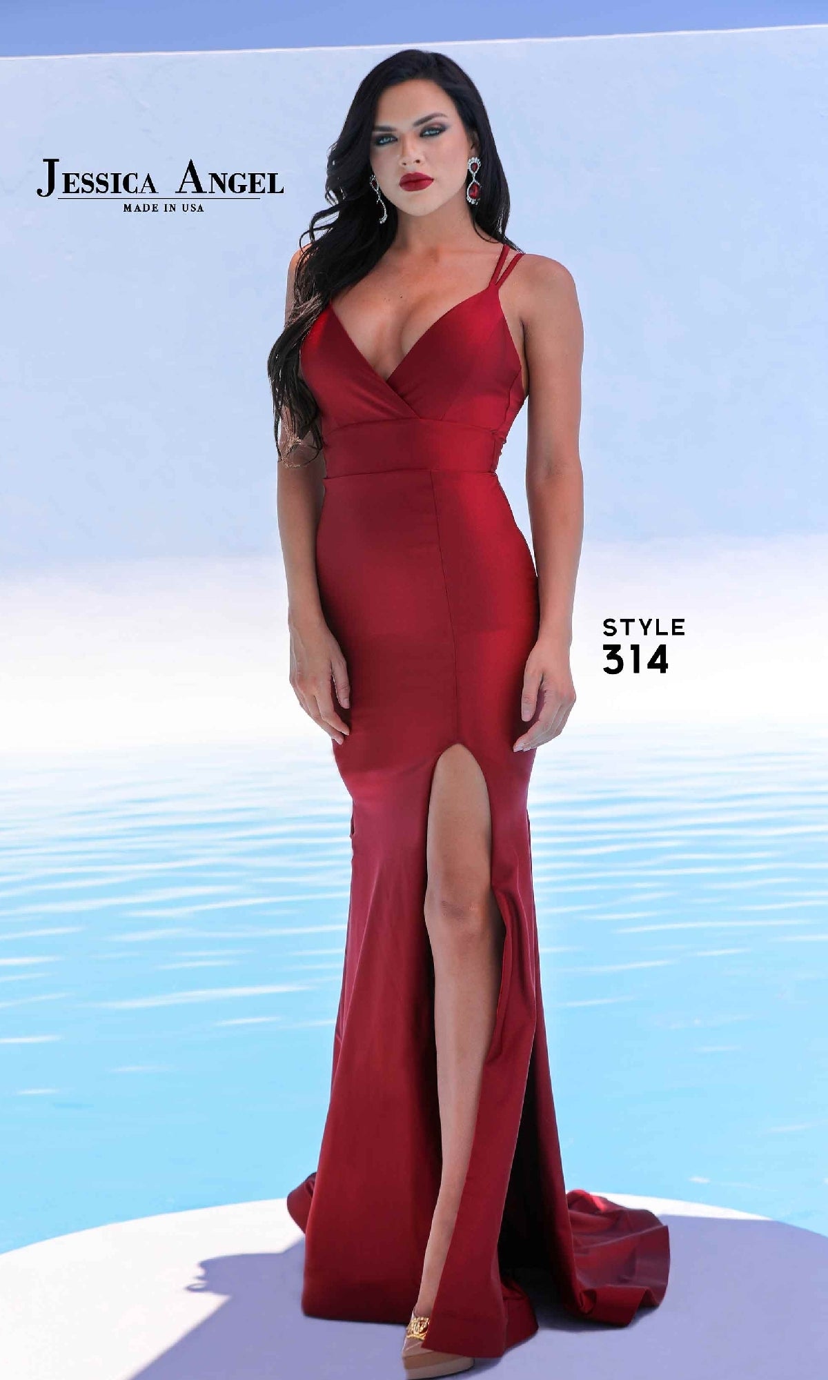 Woman in an Empire-Waist Long Prom Dress, Jessica Angel 314, fitted and sleeveless with a thigh-high slit, stands before a blue background.